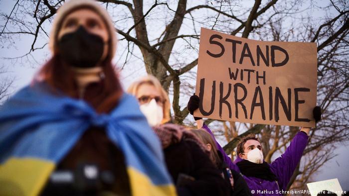 A man holds a poster that reads Stand with Ukraine in front of the Russian embassy in Berlin. (AP Photo/Markus Schreiber)