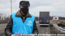 SCHASTIA, UKRAINE - MARCH 1, 2021: An employee of the Office of the United Nations High Commissioner for Refugees is seen by trucks of a UNHCR convoy carrying humanitarian aid for residents of the non-government controlled areas of Donbass at the Lugansk-Schastia crossing point. Eleven trucks loaded with supplies for reconstruction of buildings destroyed in shelling attacks are to pass through the crossing point. Alexander Reka/TASS