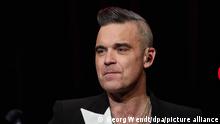 Popsänger Robbie Williams steht auf der Bühne im Kehrwieder Theater und gibt ein Fankonzert. (zu dpa Trotz Lockdown-Ende: Robbie Williams bleibt zu Hause) +++ dpa-Bildfunk +++