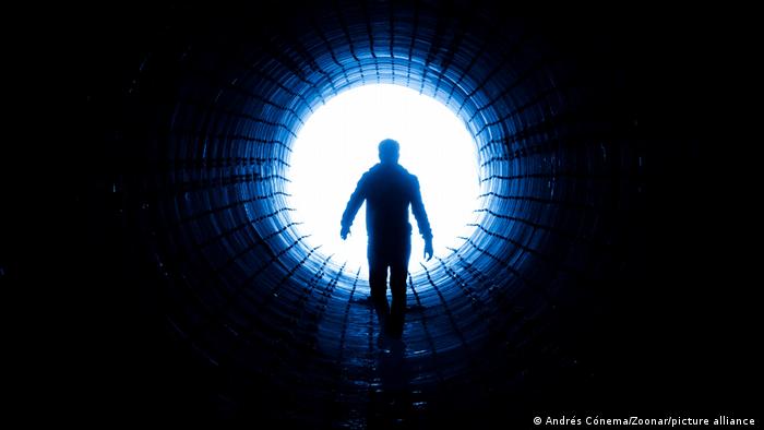 Person vor dem hellen Ende eines Tunnels