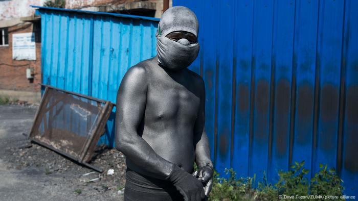 A worker covered in graphite dust at a warehouse where graphite is processed