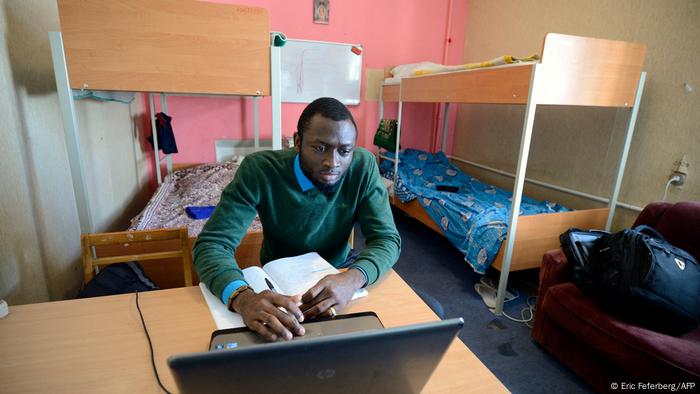 An African university student with a notebook inside a dorm.
