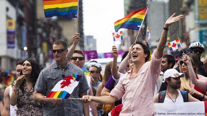 Canadian Prime Minister Justin Trudeau, surrounded by revelers, waves a Canadian Pride Flag at Pride Toronto