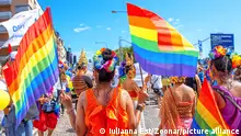 Pessoas portando bandeiras de arco-íris na rua