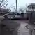 Обгоревший микроавтобус Mercedes и разрушенный забор после обстрела в районе Мариуполя