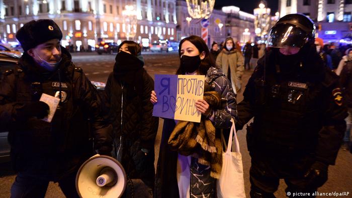 A woman with a placard surrounded by security officers in Russia