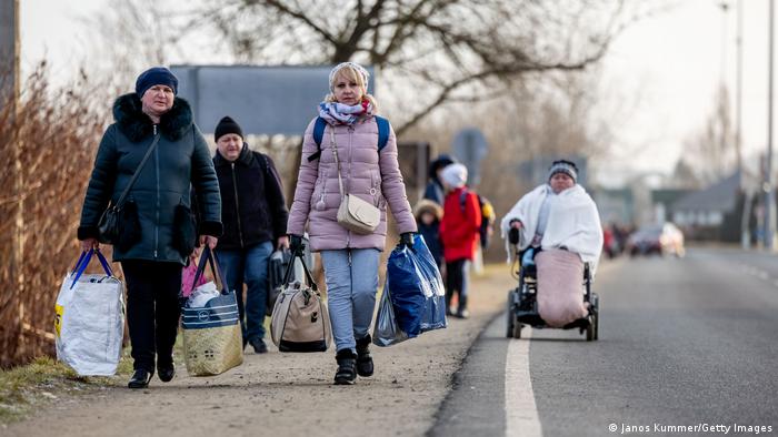 Ucranianos cargan sus pertenencias en el cruce fronterizo de Astely-Beregsurany mientras escapan a Hungría. Se han formado largas colas en la frontera, ya que la gente está desesperada por irse.