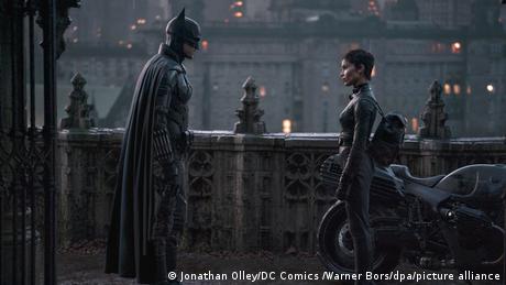 Filmstill 'The Batman': Robert Pattinson as Batman and Zoe Kravitz as Catwoman look at each other in an urban setting.