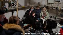 25.02.2022, Ukraine, Kiew: Menschen suchen Schutz in einem Keller eines Gebäudes, während die Sirenen neue Angriffe ankündigen. Russland hat am Donnerstag einen umfassenden Angriff auf die Ukraine gestartet und Städte und Stützpunkte mit Luftangriffen oder Granaten beschossen. Foto: Emilio Morenatti/AP/dpa +++ dpa-Bildfunk +++