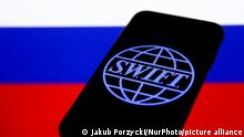 SWIFT (Society for Worldwide Interbank Financial Telecommunication) logo displayed on a phone screen and Russian flag displayed on a screen in the background are seen in this illustration photo taken in Krakow, Poland on January 23, 2022. (Photo by Jakub Porzycki/NurPhoto)