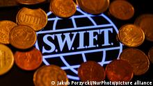 SWIFT (Society for Worldwide Interbank Financial Telecommunication) logo displayed on a phone screen and coins are seen in this illustration photo taken in Krakow, Poland on January 23, 2022. (Photo by Jakub Porzycki/NurPhoto)