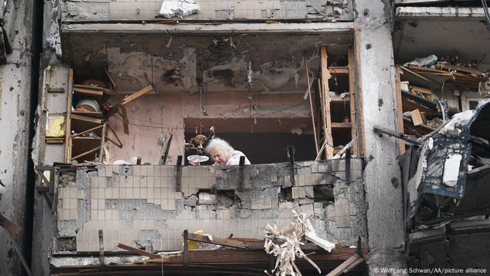 An elderly woman amid a severely damaged building in Kyiv