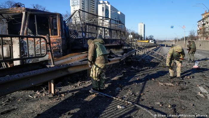 Soldados ucranianos investigan restos de un vehículo militar incendiado por bombardeos rusos en Kiev.