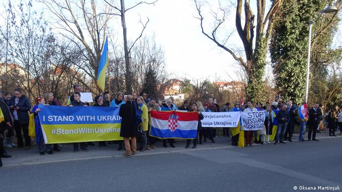 An einer Straße in der kroatischen Hauptstadt Zagreb stehen mehrere Menschen mit Bannern in der Hand auf denen sie ihre Solidarität mit der Ukraine bekunden