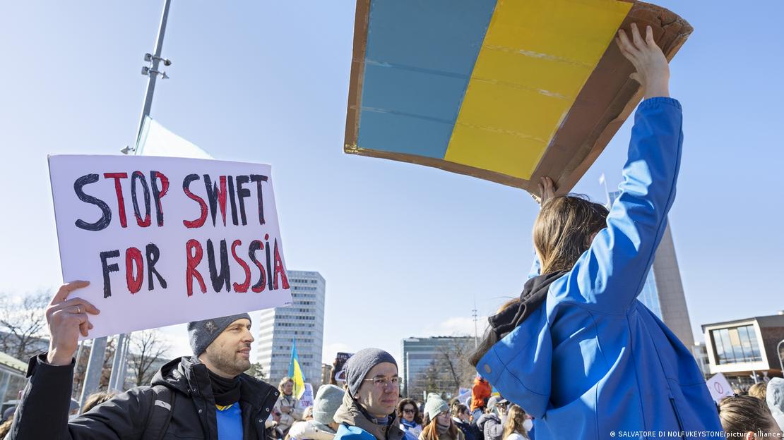 Manifestantes portando cores da bandeira ucraniana e cartaz 