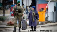 TOPSHOT - A Slovak soldier helps a Ukrainian woman to carry her luggage after after she crossed the border in Vysne Nemecke, eastern Slovakia, on February 26, 2022. - Ignoring warnings from the West, Russian President Vladimir Putin unleashed a full-scale invasion of Ukraine that the UN refugee agency said has forced almost 116,000 people to flee to neighbouring countries. (Photo by PETER LAZAR / AFP) (Photo by PETER LAZAR/AFP via Getty Images)