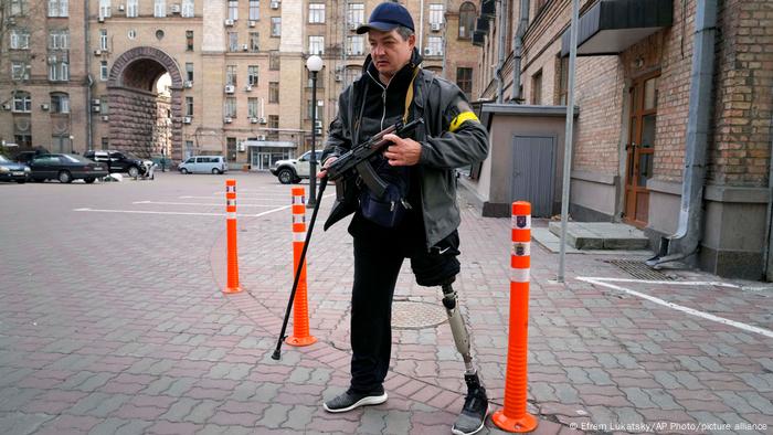 A man standing on a street in Kyiv holding a gun