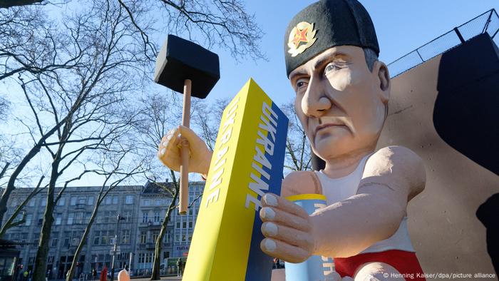 A Cologne Carnival float title the good old days depicts Vladimir Putin in a Soviet hat holding a large hammer, preparing to strike a post labeled Ukraine in the colors of Ukraine's flag. 