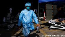 A medical worker wearing personal protective equipment (PPE), walks at a makeshift coronavirus disease (COVID-19) treatment area, outside a hospital in Hong Kong, China February 28, 2022. REUTERS/Tyrone Siu