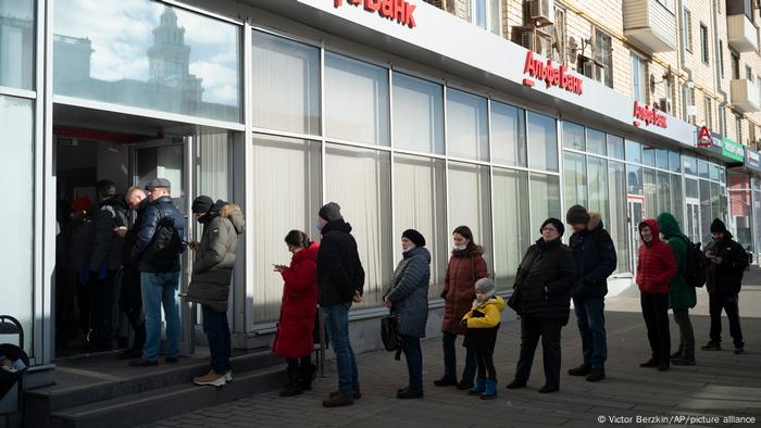 Люди стоят в очереди, чтобы снять деньги в одном из банкоматов в Москве 