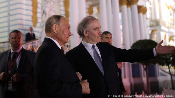 Putin and Gergiev stand together outside of a building.