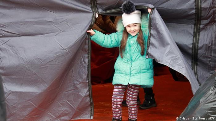 A smiling Ukranian child in a makeshift tent in Romania