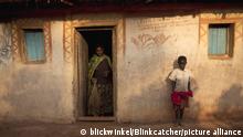 Frau mit Reisigbesen im Eingang eines Hauses, Junge steht an der Hauswand, Burundi, Karuzi, Buhiga | woman with besom standing in entrance, boy leaning against facade, Burundi, Karuzi, Buhiga