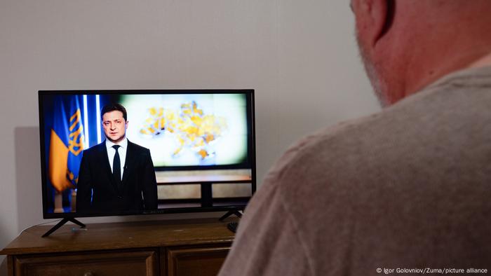 Foto de una persona que mira un video de Volodimir Zelensky.