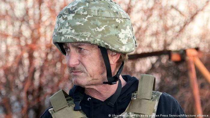 Sean Penn wears a military helmet and bulletproof vest.