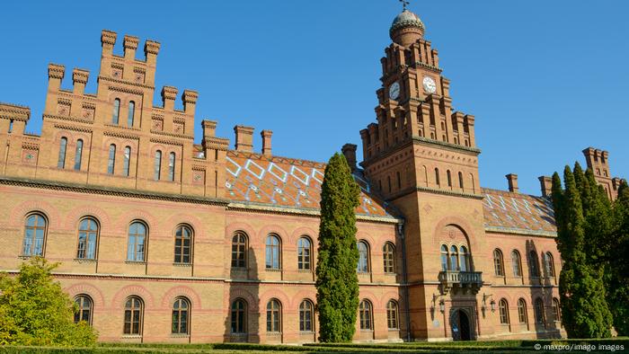 Oświetlona słońcem elewacja z czerwonej cegły dawnej siedziby arcybiskupów Bukowinii i Dalmacji.