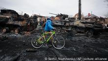 A man walks past the remains of Russian military vehicles in Bucha, close to the capital Kyiv, Ukraine, Tuesday, March 1, 2022. Russia on Tuesday stepped up shelling of Kharkiv, Ukraine's second-largest city, pounding civilian targets there. Casualties mounted and reports emerged that more than 70 Ukrainian soldiers were killed after Russian artillery recently hit a military base in Okhtyrka, a city between Kharkiv and Kyiv, the capital. (AP Photo/Serhii Nuzhnenko)