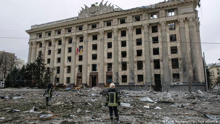 Rescuers stand in front of the bombed out administrative building in Kharkiv's Freedom Square on March 1