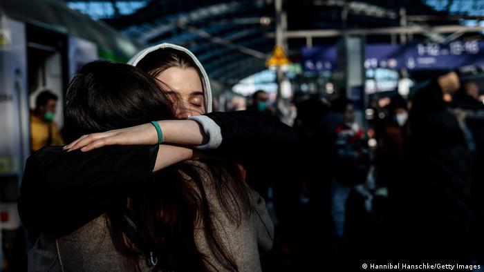Two women hug each other deeply after refugees from the Ukraine arrive at the main train station in Berlin