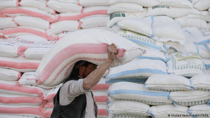  A worker carries a sack of wheat flour outside a wholesale food shop in Sanaa, Yemen.