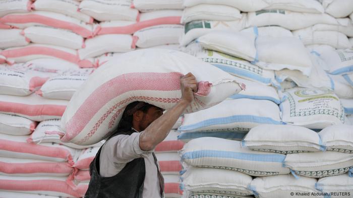  A worker carries a sack of wheat flour outside a wholesale food shop in Sanaa, Yemen.