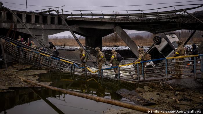 Ukrainian soldiers cross a destroyed bridge, on the outskirts of Kyiv, Ukraine, Wednesday, March 2. 2022.