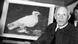 Black and white photo of Pablo Picasso stood next to a painting of a dove Black and white photo of Pablo Picasso stood next to a painting of a dove