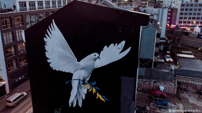 Huge painting of dove of peace on outside wall of Frankfurt building, with olive branch with Ukrainian flag colors in claws.
