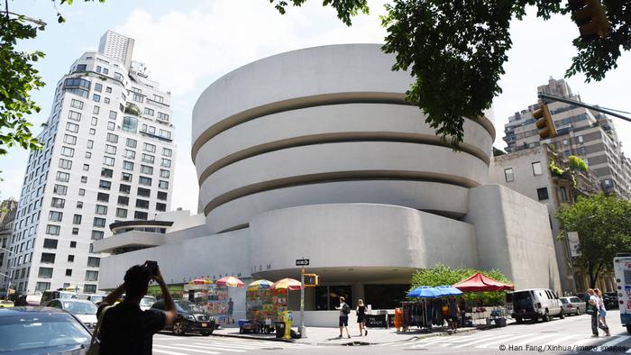 Guggenheim Museum from outside: circular building with tree in front.
