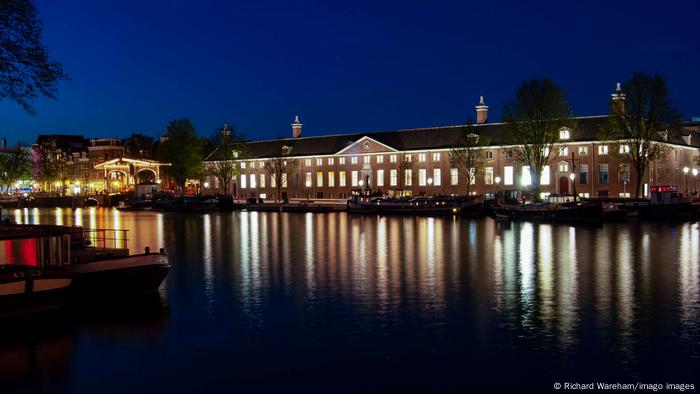 Hermitage Amsterdam museum with lights reflected in the Amstel River in the early evening.