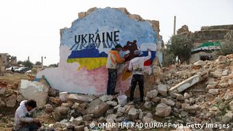 Syrian artists paint a mural depicting the colours of the Russian and Ukrainian flags