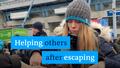 A woman hands out relief supplies, with the text: Helping other after escaping