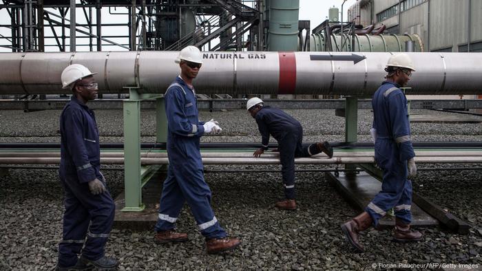 A picture of Nigerian gas workers walking walk past a pipeline 