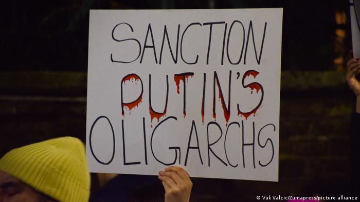 A protester in London holds a 'Sanction Putin's Oligarchs' placard