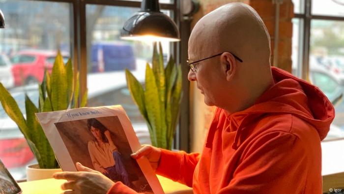 Igor looks at an album by singer Suzi Quatro at a cafe in Lviv, wearing an orange sweatshirt