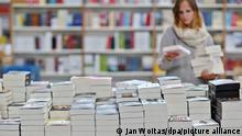 Eine Frau bestückt am 11.03.2015 einen Büchertisch in der Messebuchhandlung auf der Buchmesse Leipzig (Sachsen). Auf der Messe in der Stadt Leipzig werden Tausende Bücher vorgestellt. Foto: Jan Woitas/dpa ACHTUNG: Dieses Bild hat dpa bereits im Bildfunk gesendet. +++(c) dpa - Nachrichten für Kinder+++