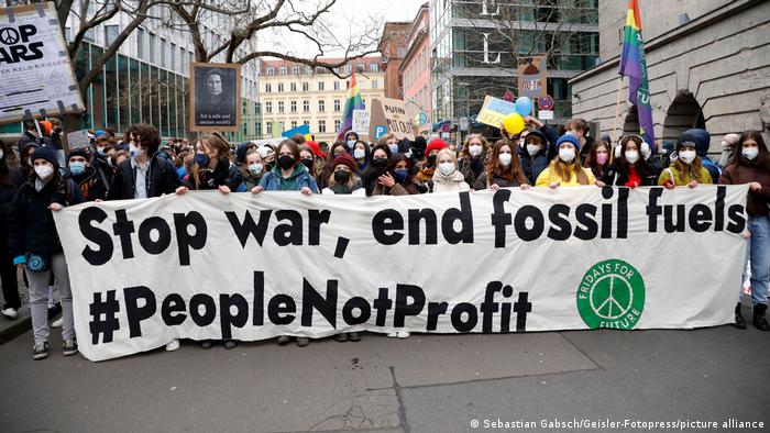 Fridays for Future activits carry a banner in Berlin demanding an end to war and fossil fuels.