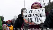 Eine Frau hält ein Schild mit der Aufschrift «Give peace a chance Putin» (Putin, gib dem Frieden eine Chance), während sie vor der russischen Botschaft gegen Russlands Angriff auf die Ukraine protestiert. Russische Truppen haben ihren erwarteten Angriff auf die Ukraine gestartet. +++ dpa-Bildfunk +++