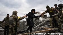 TOPSHOT - A woman is assisted by Ukrainian servicemen while people cross a destroyed bridge as they evacuate the city of Irpin, northwest of Kyiv, during heavy shelling and bombing on March 5, 2022, 10 days after Russia launched a military in vasion on Ukraine. (Photo by Aris Messinis / AFP) (Photo by ARIS MESSINIS/AFP via Getty Images)