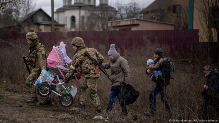 Russia Ukraine War, two soldiers carry as baby carriage, three women walk behind them in a residential neighborhood 